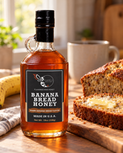 Load image into Gallery viewer, Firebee Banana Bread Honey 19oz glass bottle beside a sliced loaf of banana bread with butter and a ripe banana