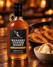 Load image into Gallery viewer, Firebee Bananas Foster Honey 19oz glass bottle beside a skillet of caramelized bananas and vanilla ice cream