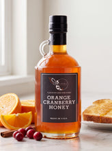 Load image into Gallery viewer, Firebee Orange Cranberry Honey 19oz glass bottle with fresh oranges and cranberries